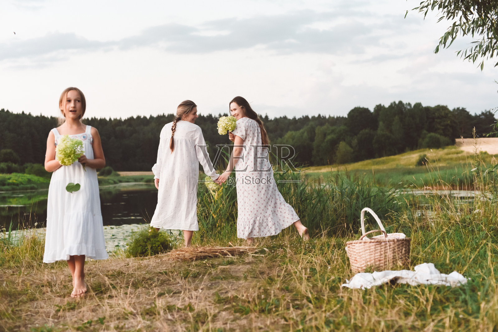 穿着白色睡裙的女孩在湖边摆姿势，温暖的夏日照片摄影图片