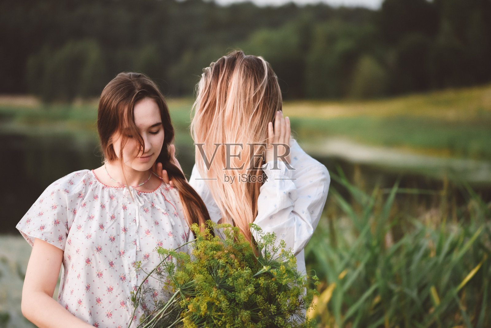 穿着白色长睡袍的女孩在湖边摆姿势。温暖的夏日。照片摄影图片
