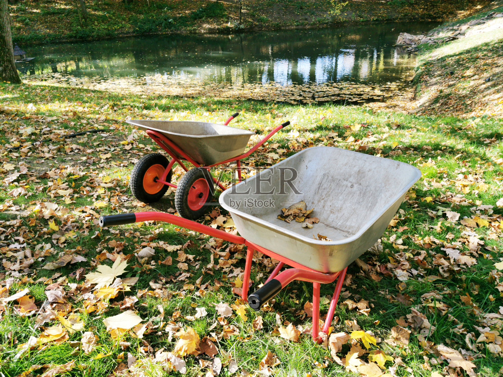 公园里空荡荡的灰色金属手推车。16、收集秋叶，收集垃圾，运输沙粒。季节性景观。照片摄影图片