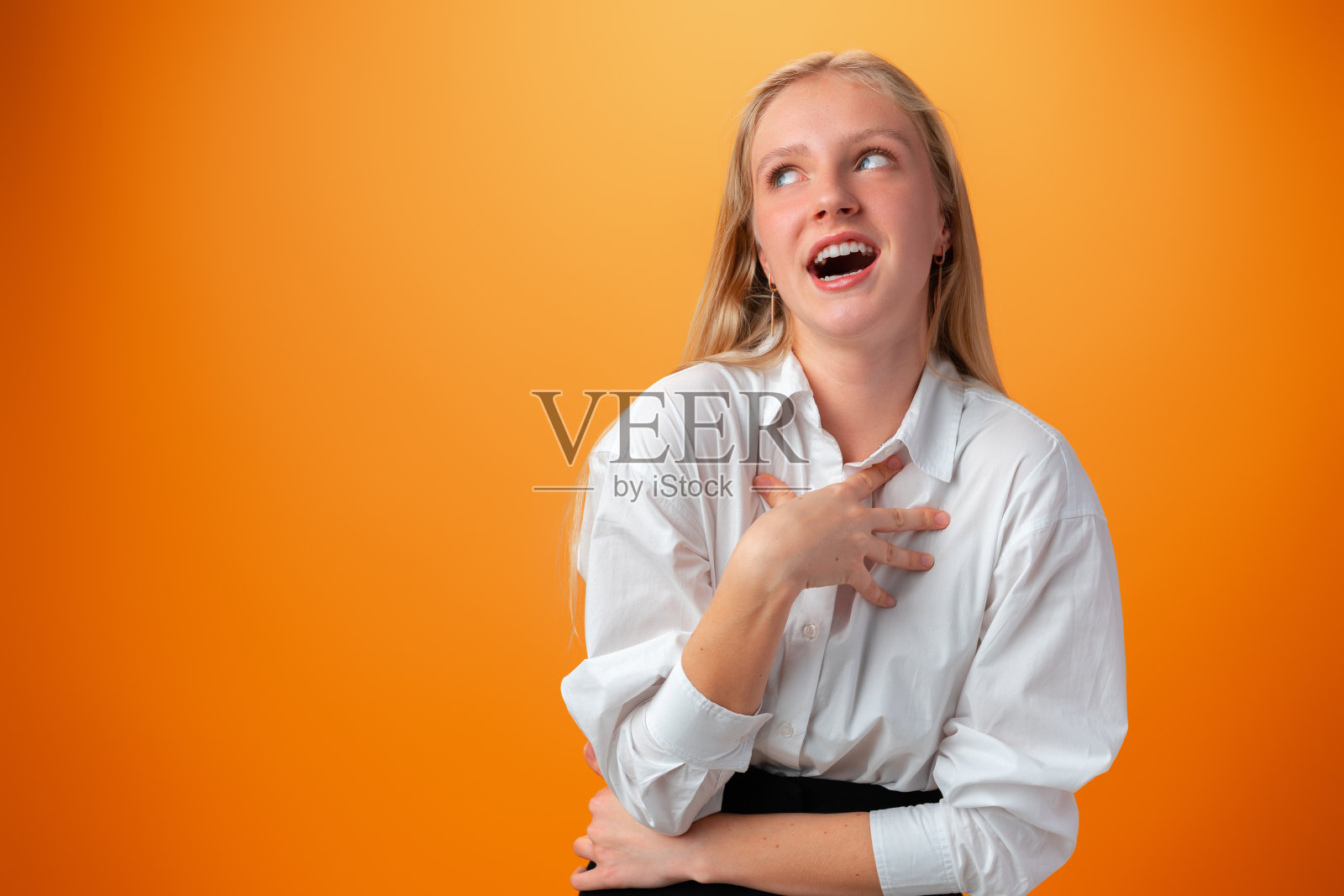 在橙色背景下微笑的年轻少女的肖像照片摄影图片