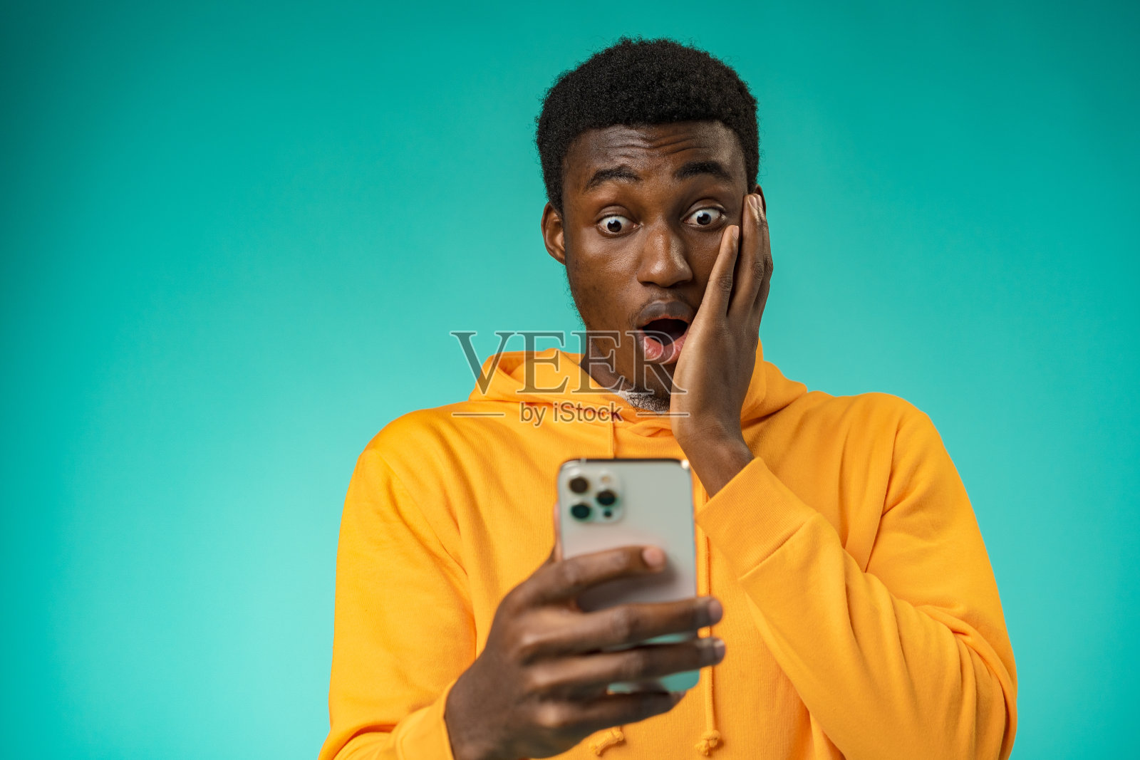 激动的黑人在演播室里用手机读好消息照片摄影图片