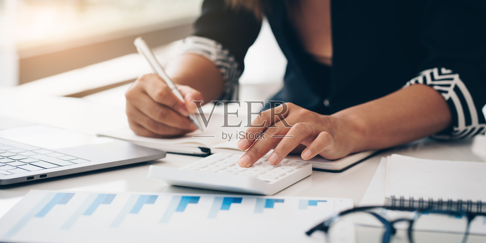 商业女性手握铅笔和财务文件看银行储蓄帐户申请笔记本电脑。帐户或储蓄或保险概念。照片摄影图片