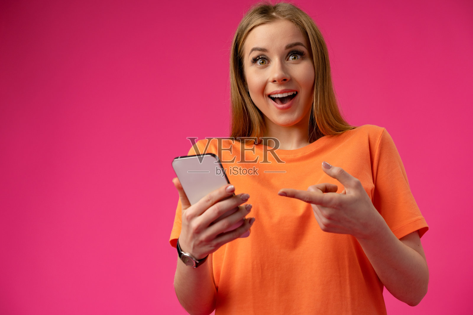 激动的年轻女子用手机对着演播室的背景照片摄影图片