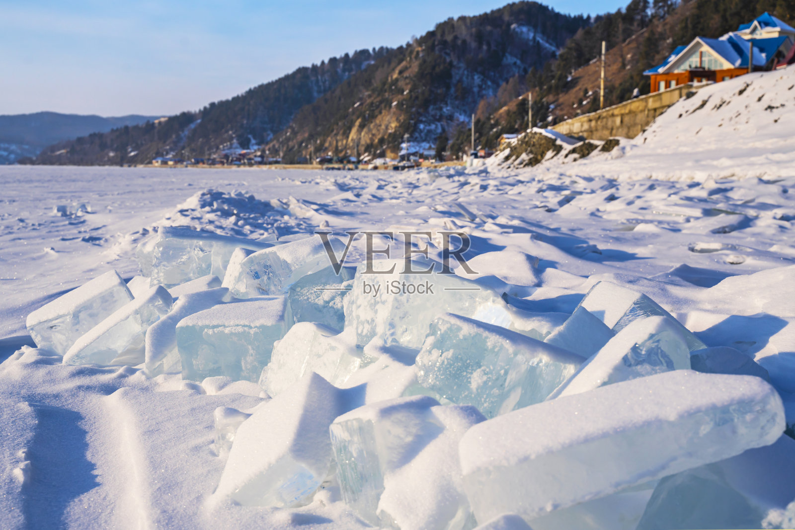 在Yuaykal的Listvyanka村附近，透明的蓝色浮冰覆盖着白雪。冰雪和冬季假期。照片摄影图片