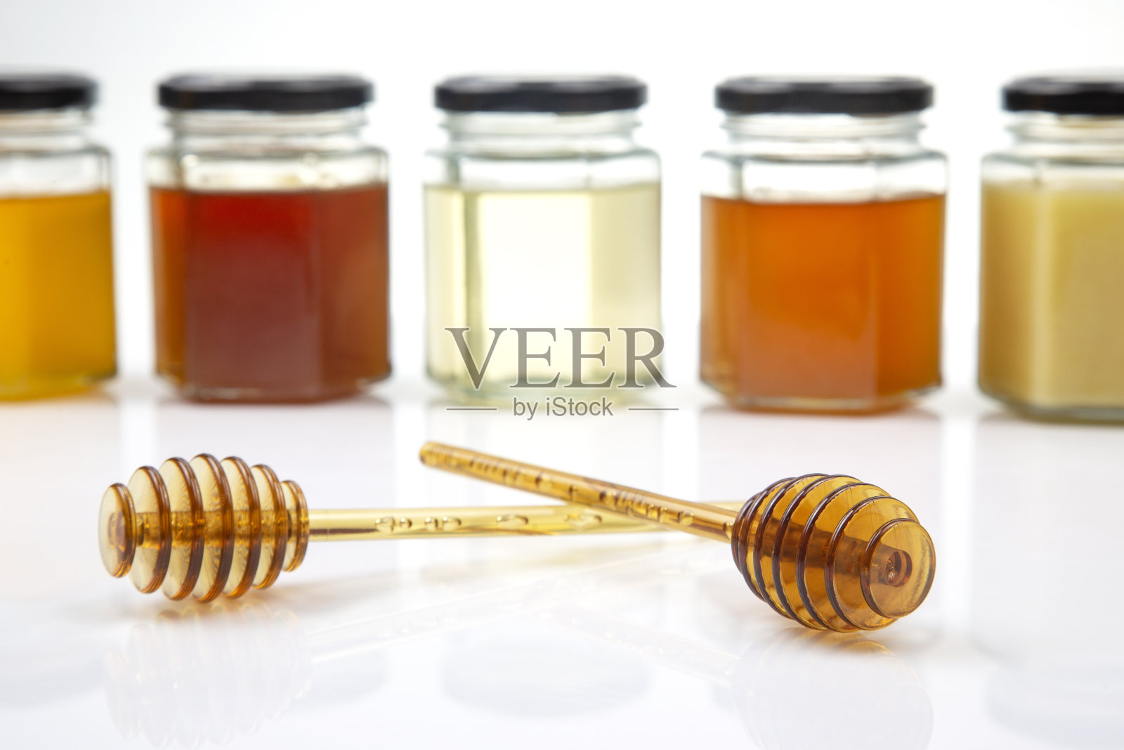 用勺子舀上新鲜的蜂蜜，在白色的背景上放上不同种类的蜂蜜。有机维生素食品照片摄影图片