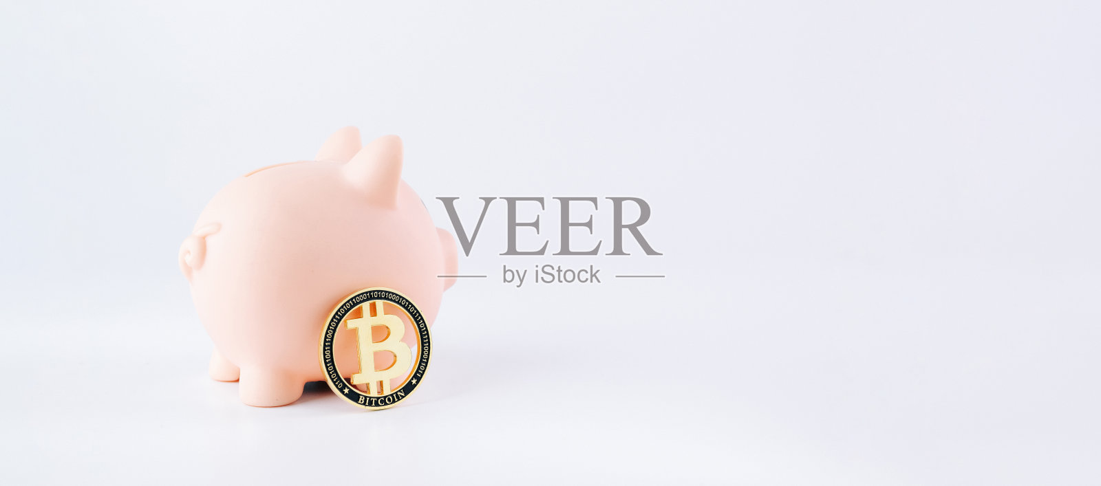 用比特币省钱。粉红色的猪银行与白色背景上的黄金比特币BTC。节约加密货币的虚拟货币概念。照片摄影图片