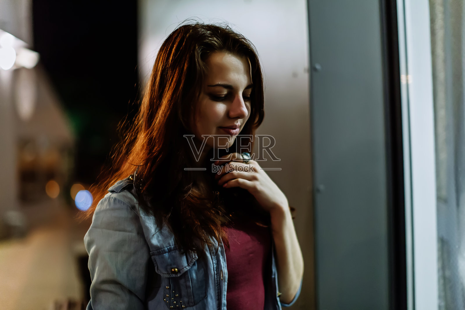 一个美丽的年轻女人的肖像在夜晚明亮的灯光街道上照片摄影图片