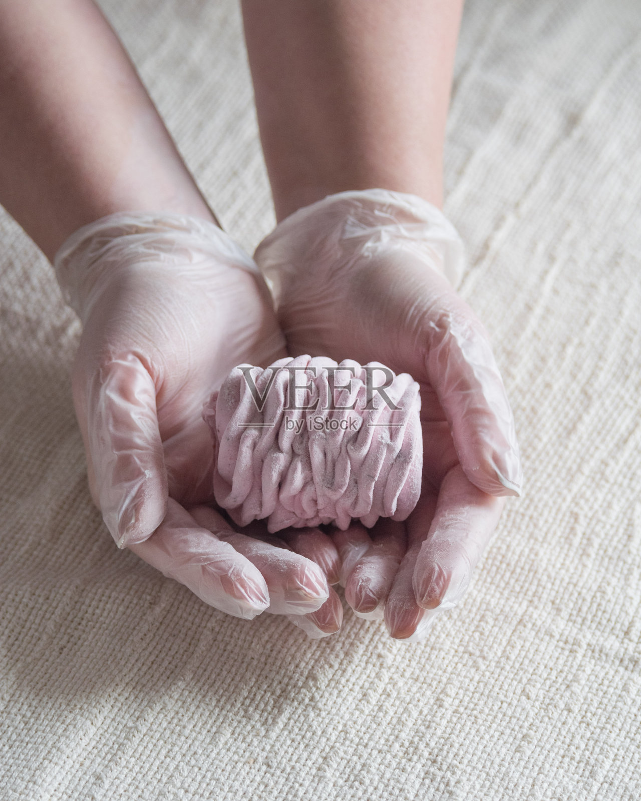 一个戴着手套的女人的手握着新鲜的自制棉花糖，轻柔的背景，选择性的聚焦照片摄影图片