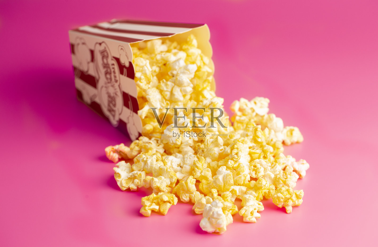 红色和白色条纹爆米花桶孤立在明亮的粉红色背景照片摄影图片