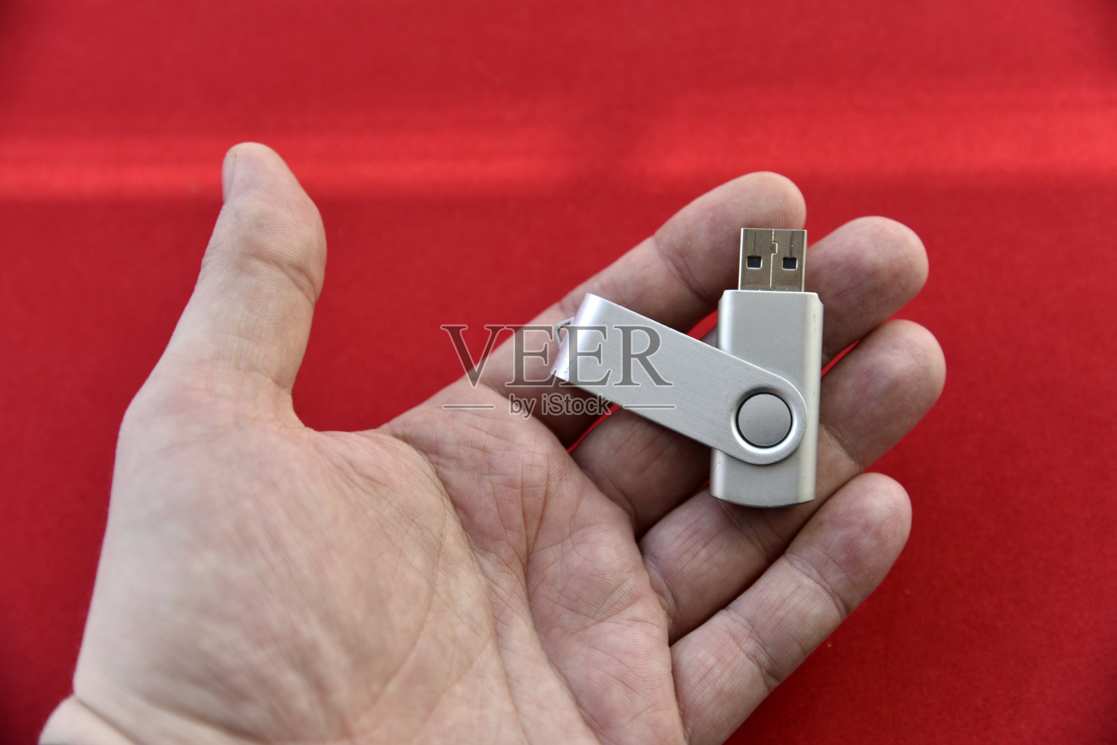 u盘放在你的手掌上，背景是红色的照片摄影图片