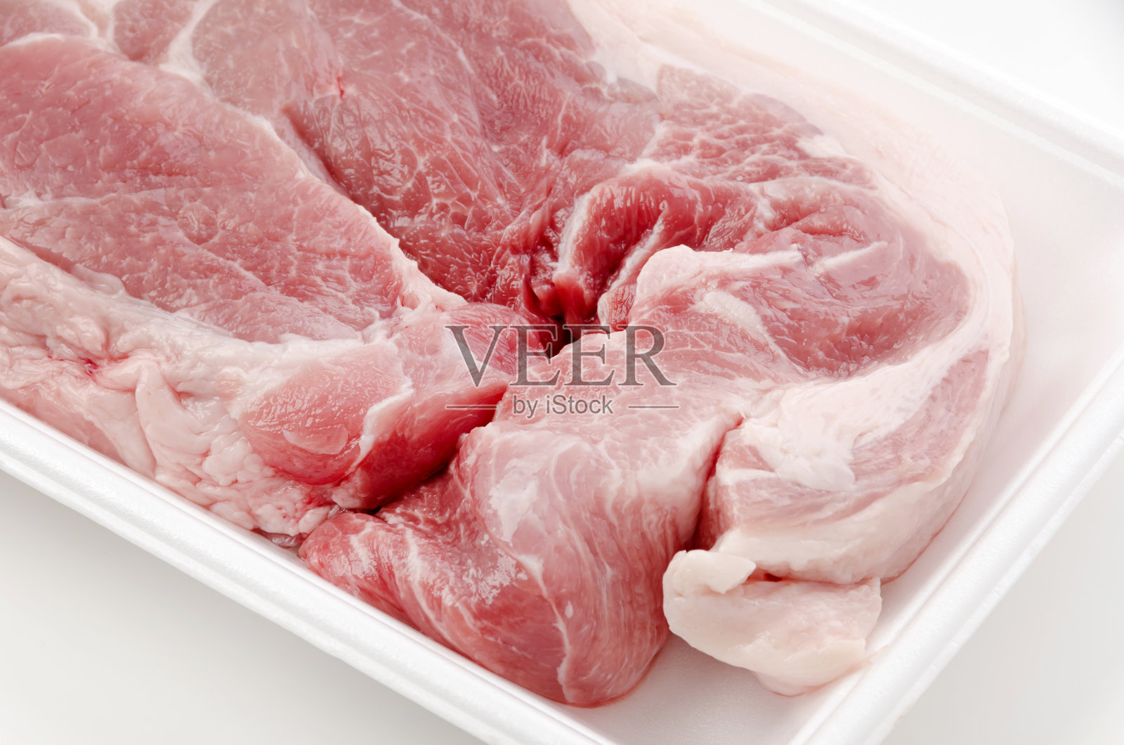 白色背景的泡沫托盘上的生猪肉照片摄影图片
