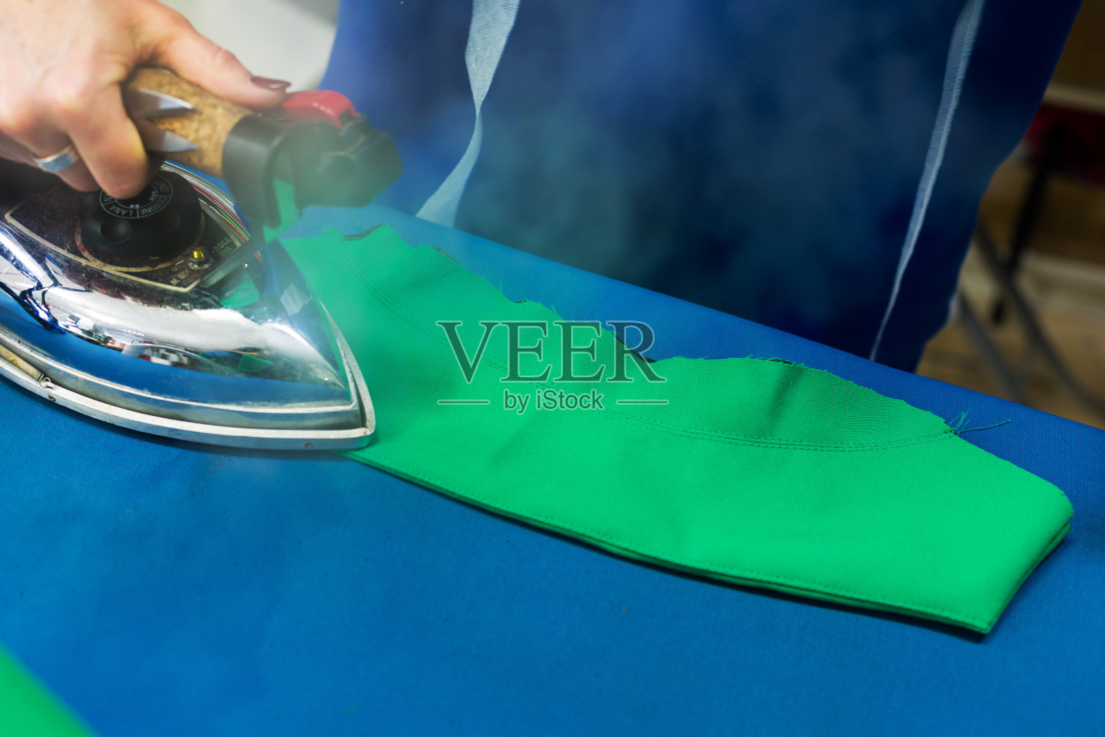 女裁缝用蒸汽熨斗烫织物照片摄影图片