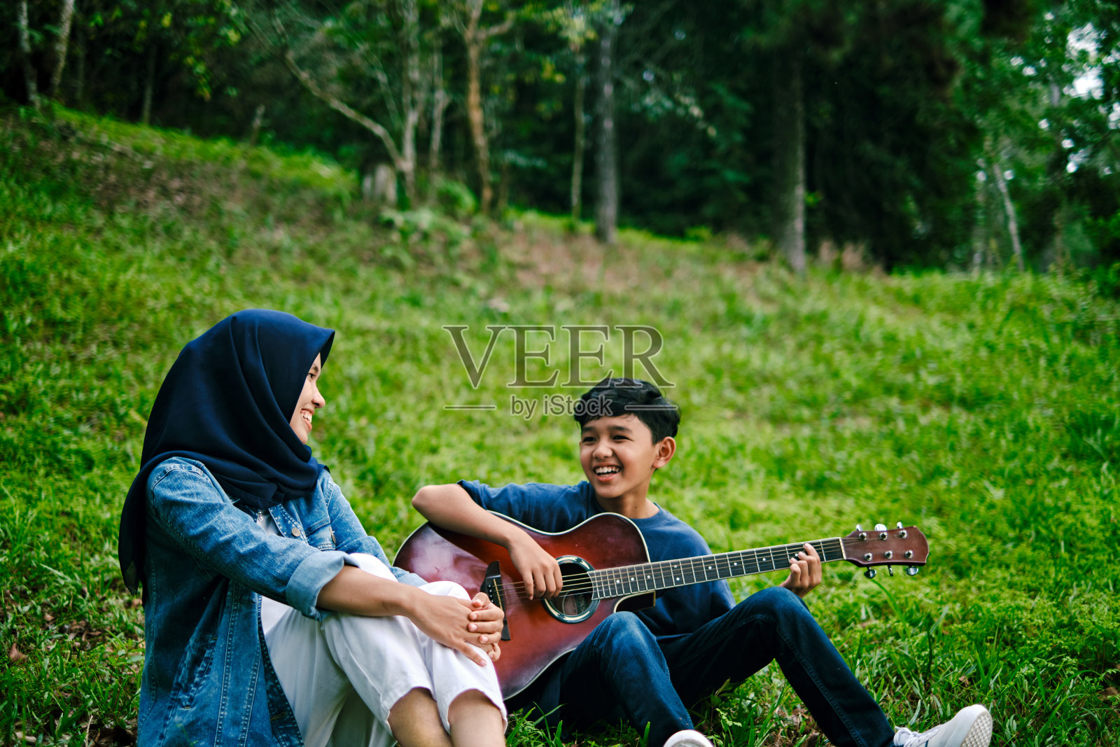 快乐的亚洲青少年朋友有乐趣唱歌和弹吉他照片摄影图片