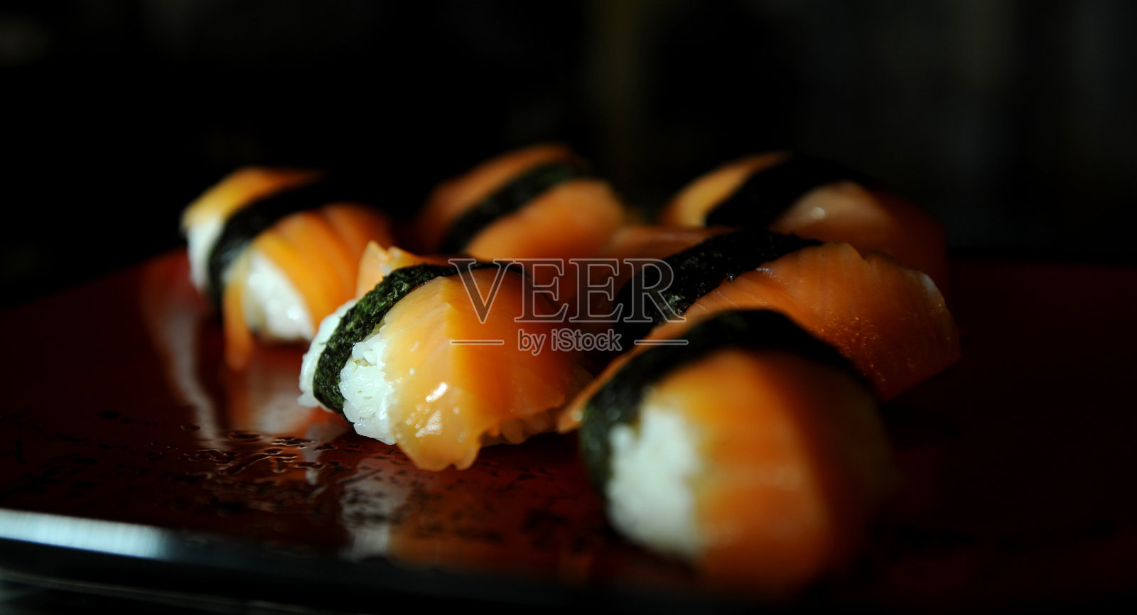 将费城寿司与金枪鱼和鳗鱼放在木板上，用筷子吃，非常美味和愉快照片摄影图片