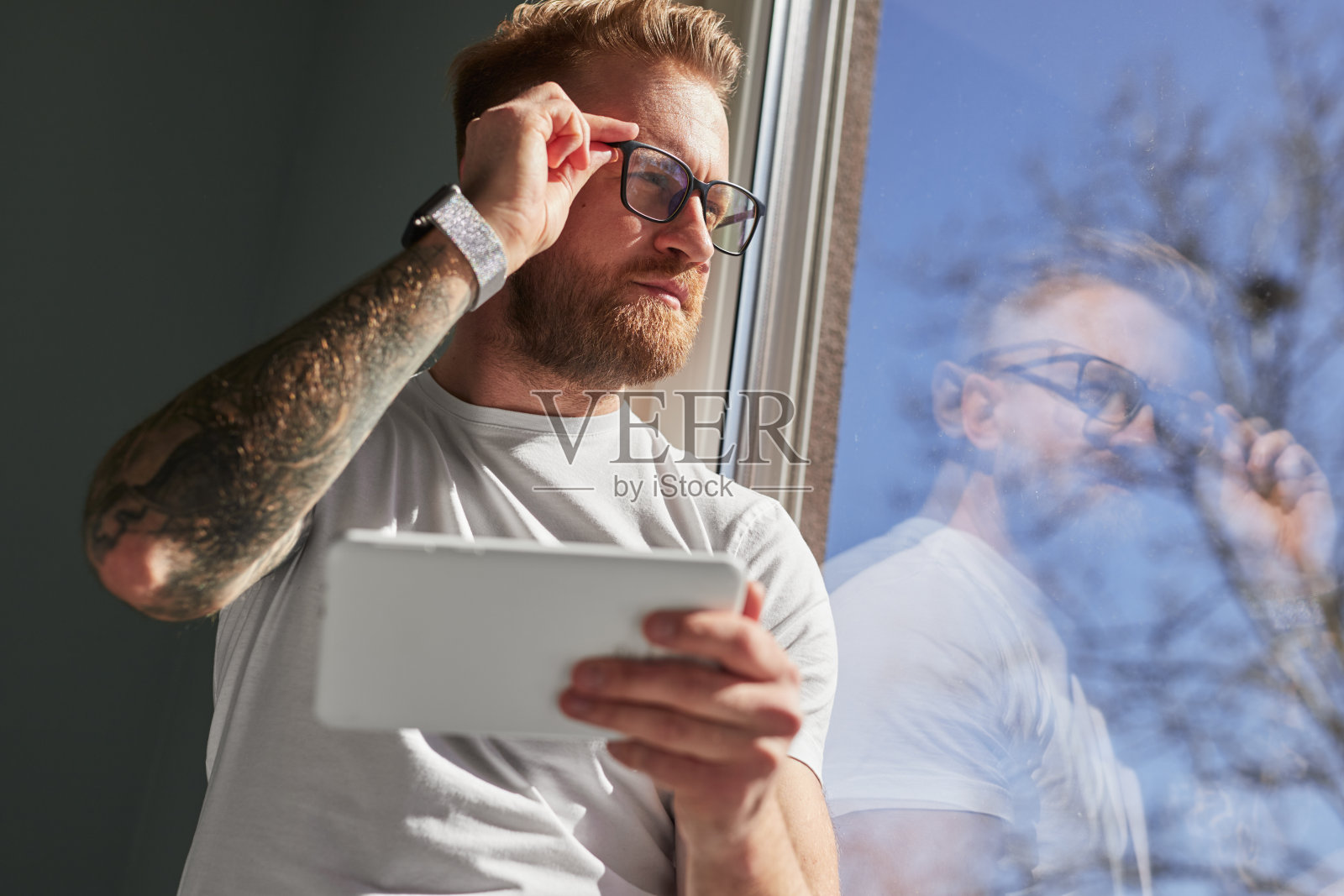 有思想的男人拿着平板电脑望着窗户照片摄影图片