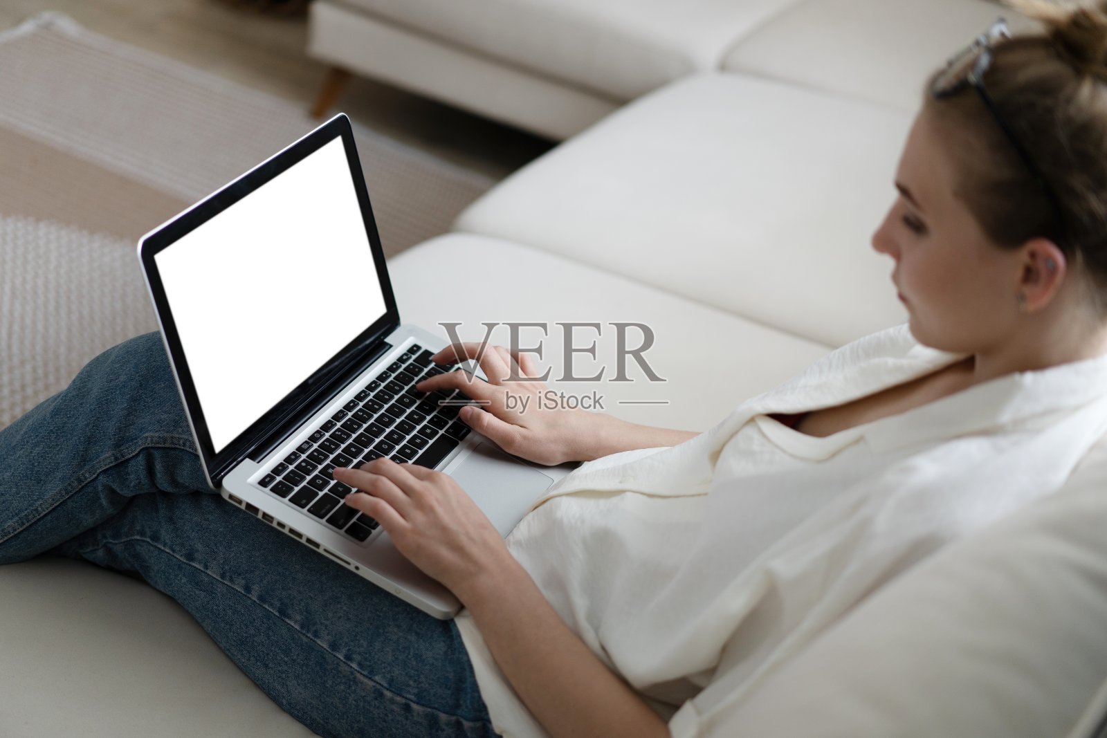 一个女人使用和打字在笔记本电脑键盘与空白的白色桌面屏幕的模型图像。照片摄影图片