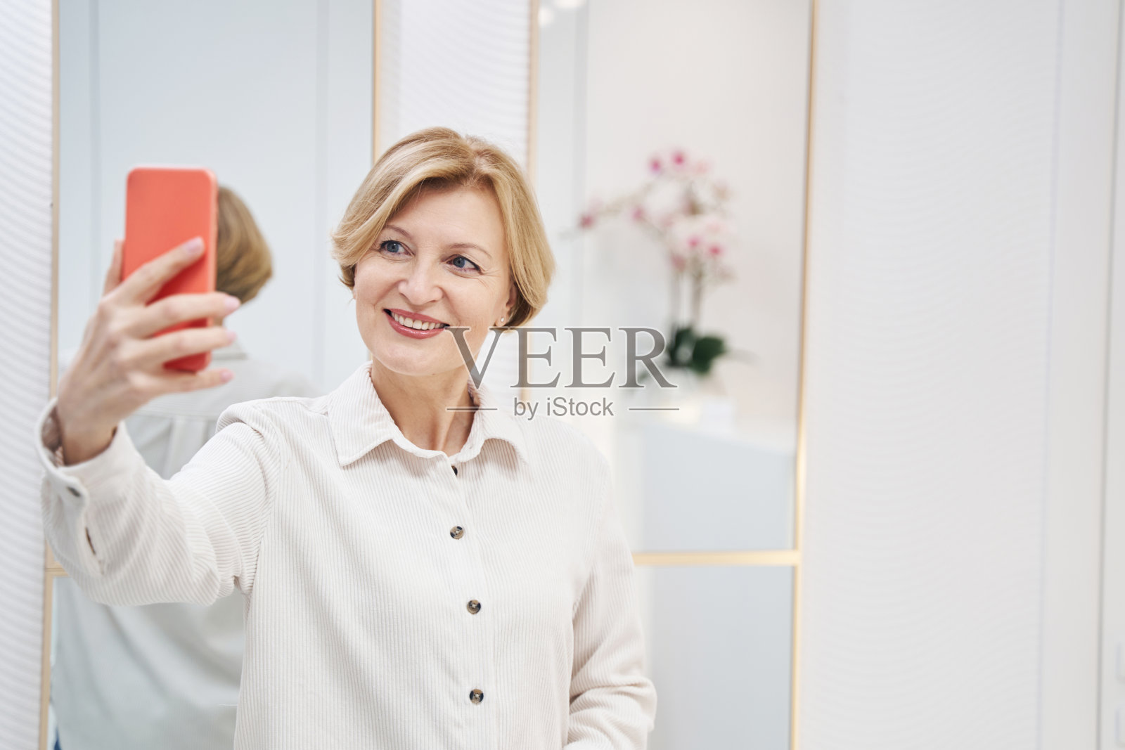 美丽的高级女性在她的小工具的相机摆姿势照片摄影图片