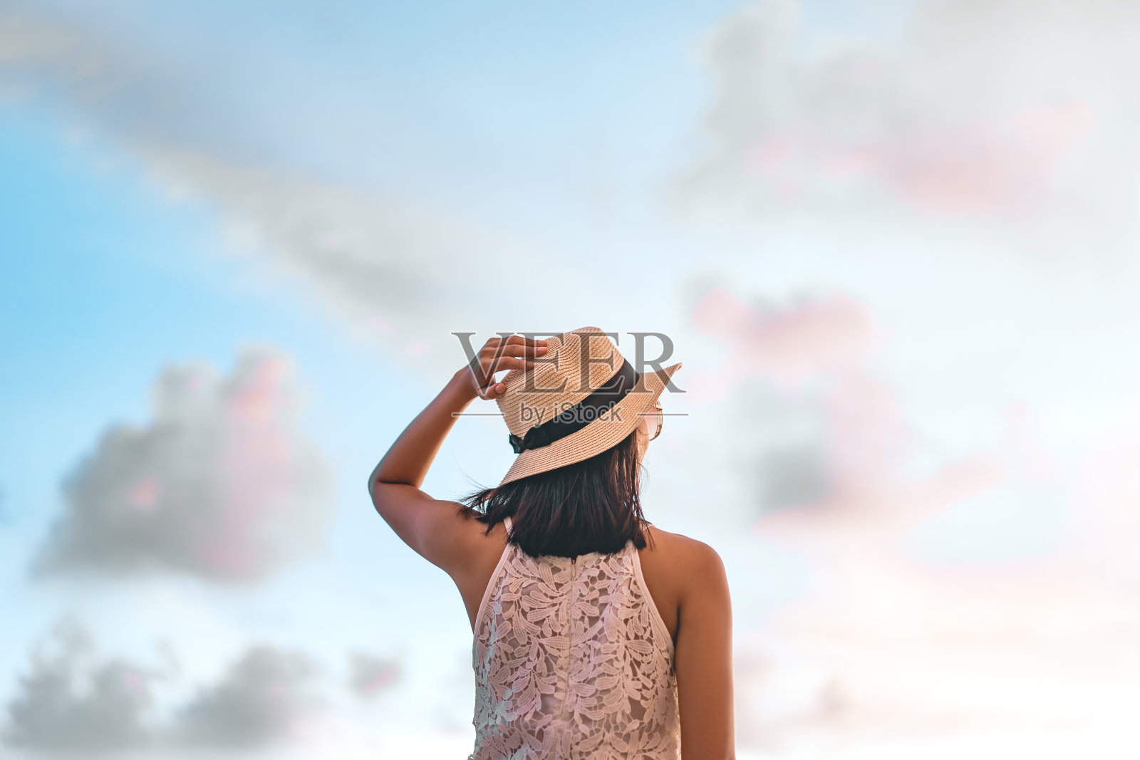 后视图年轻的亚洲妇女站在放松的阳光和天空的沙滩上。照片摄影图片