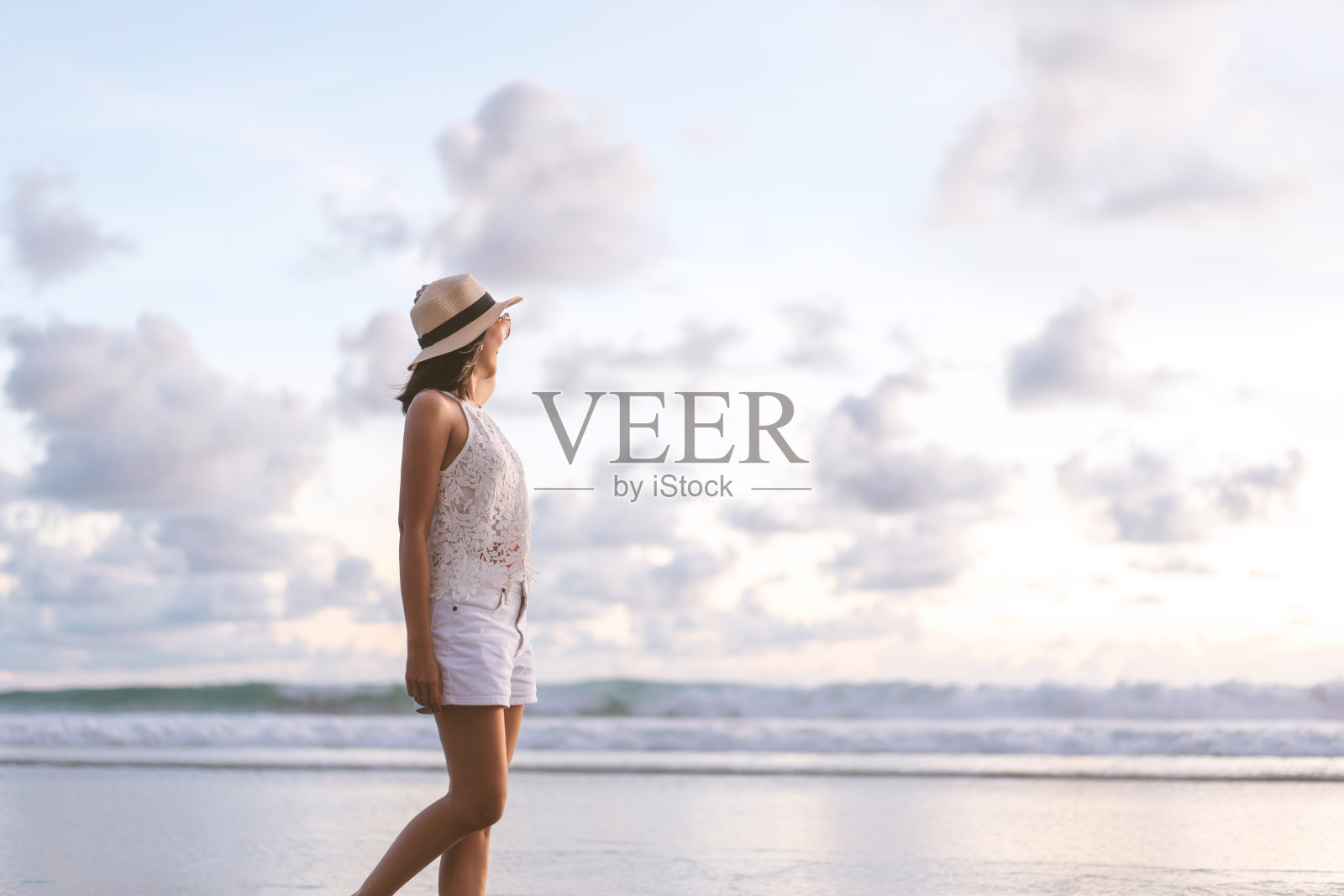 年轻的成年亚洲妇女散步放松在沙滩上日落天空。照片摄影图片