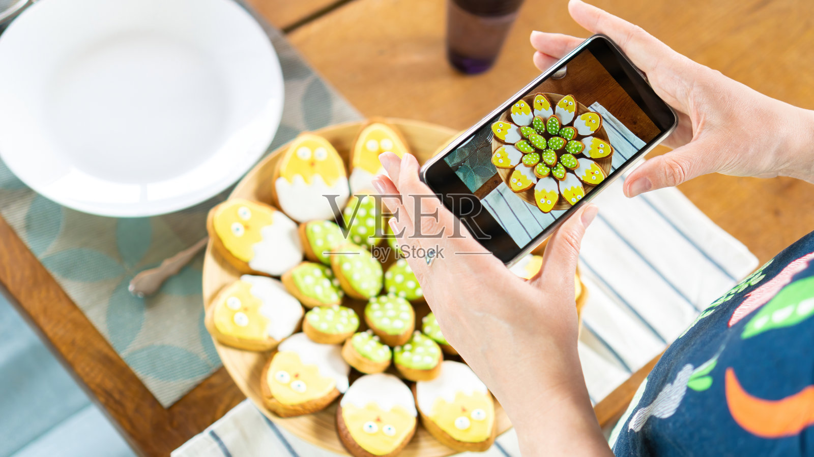 美食博主用智能手机拍摄美食。一位网红为复活节拍摄了可爱的小鸡形状的冰糖饼干。和孩子们一起为复活节做有趣的烘焙。照片摄影图片