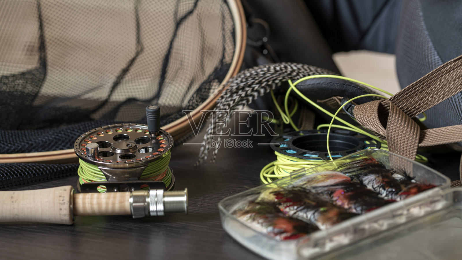 在一个破旧的黑色木制背景上，飞鱼竿，卷轴和复古鲑鱼在盒子里飞照片摄影图片