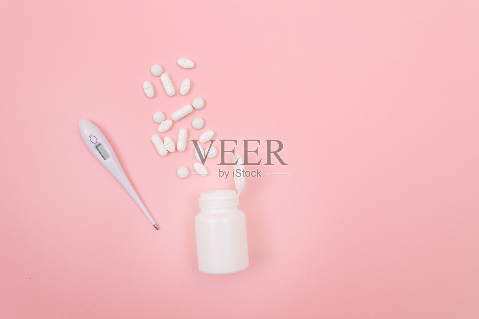 白色药丸或片剂，电子温度计粉红色背景照片摄影图片