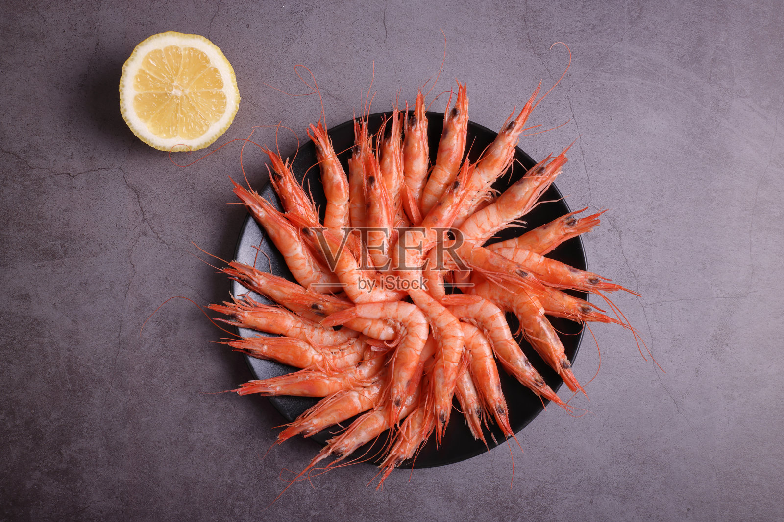 一份用柠檬装饰的熟虾。照片摄影图片