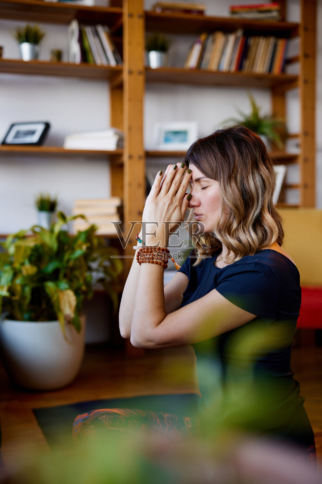 一个瑜伽女坐在家里，坐在地板上祈祷。照片摄影图片