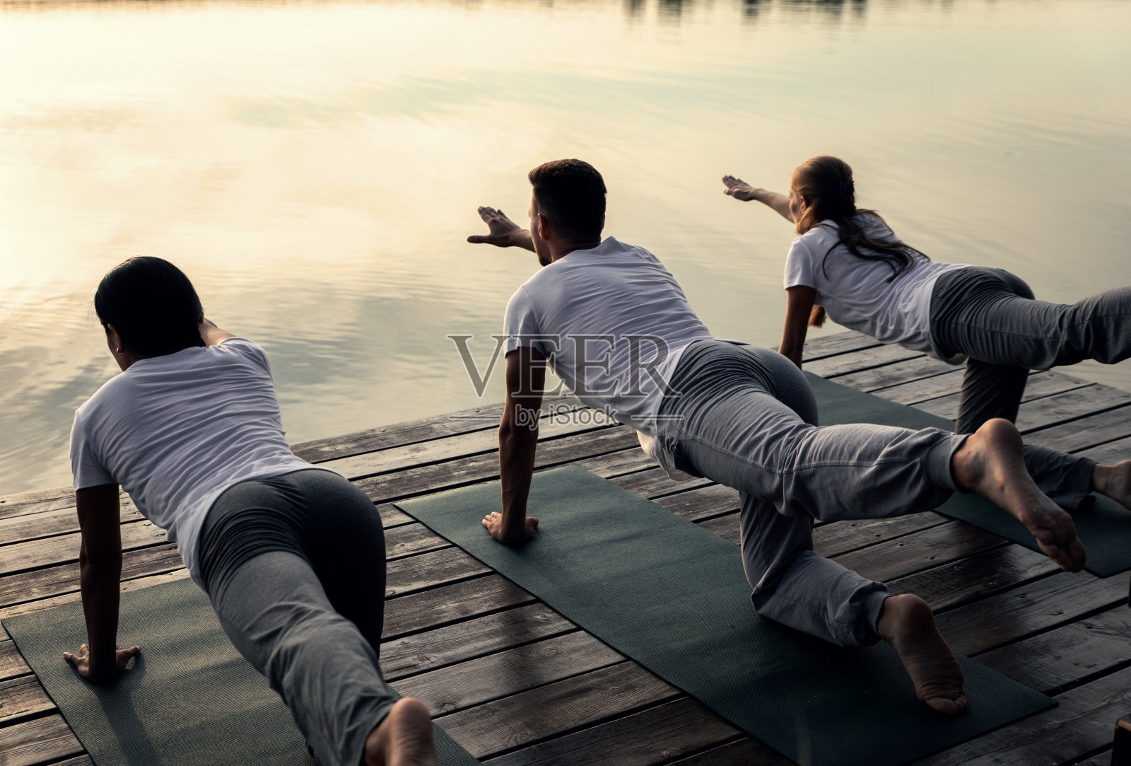 日落时分，一群人在湖边练瑜伽。照片摄影图片