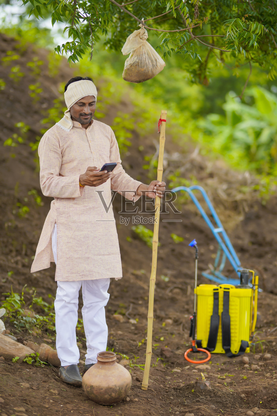 年轻的印度农民在农业领域使用智能手机。照片摄影图片