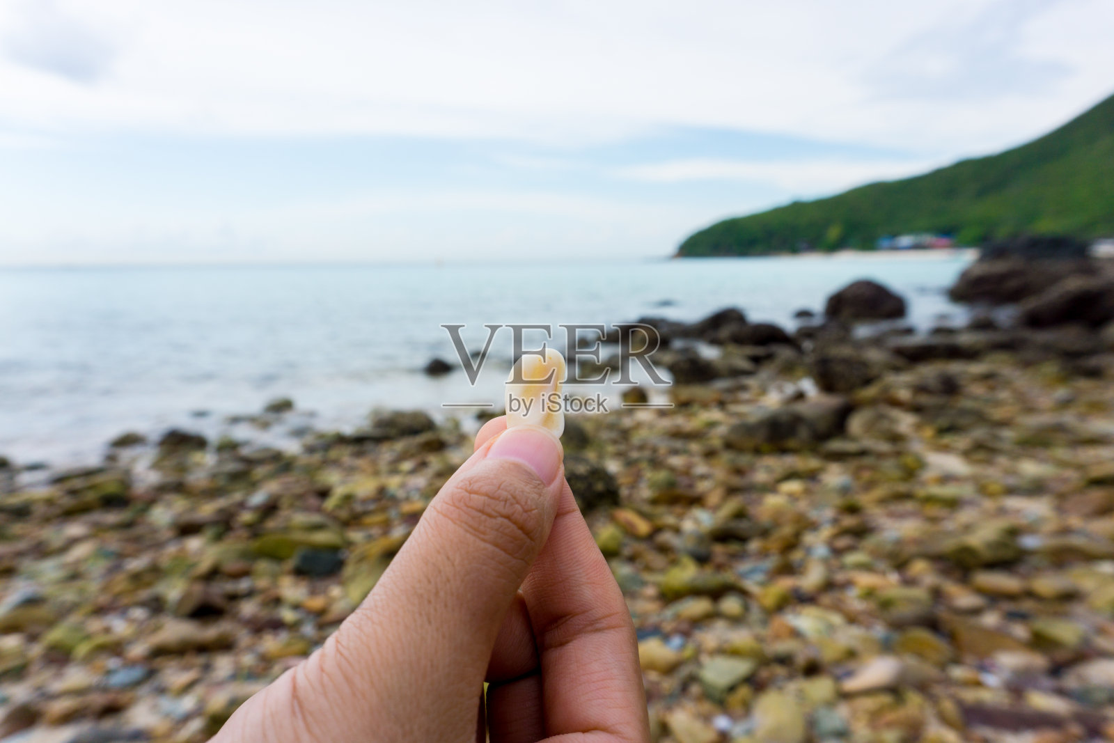 特写镜头。女人的手拿着卵石沙滩背景的小鹅卵石。照片摄影图片