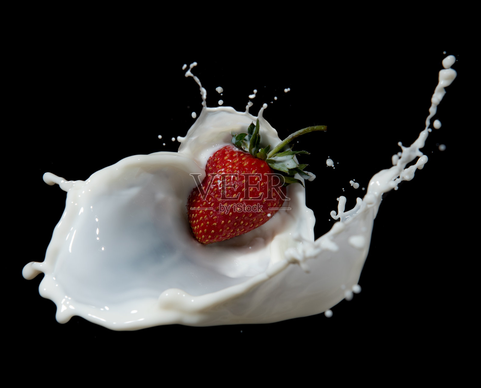 红色的草莓果实落入乳白色的溅在黑色的背景上照片摄影图片