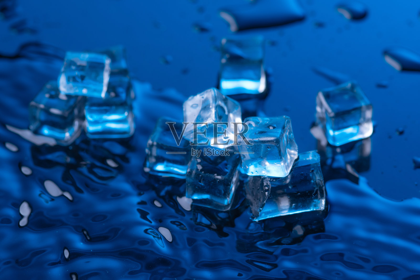 蓝色背景上散落着小水滴的冰块照片摄影图片