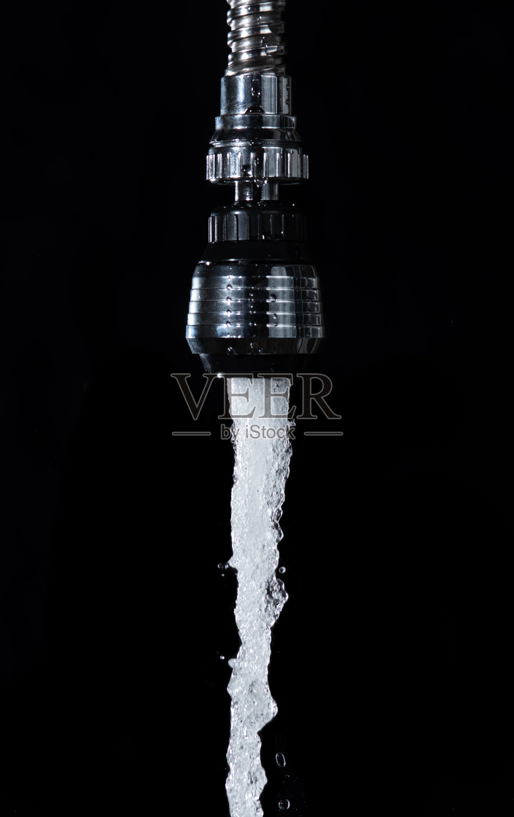 带着气泡的水在黑色的背景下从水龙头流出照片摄影图片