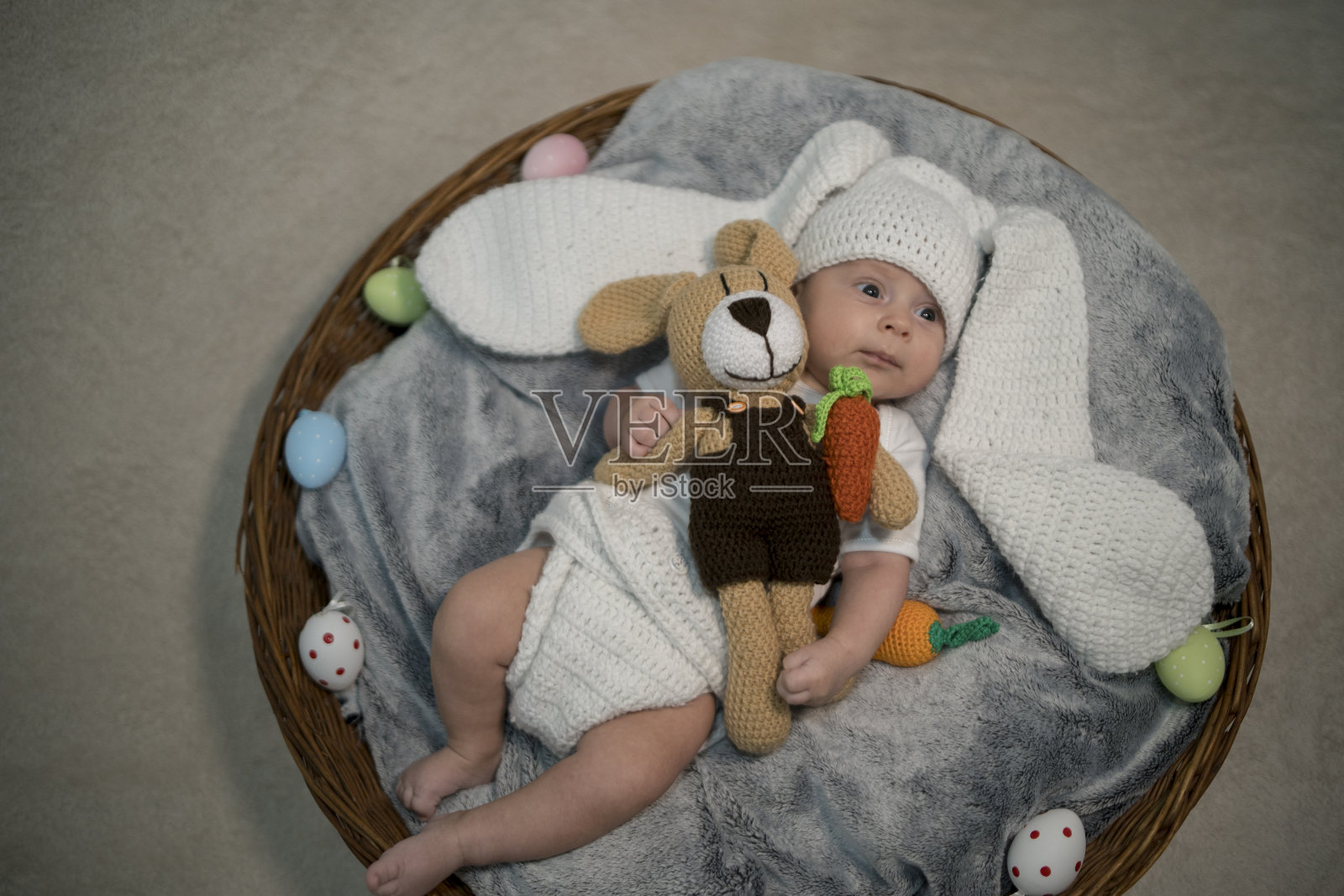 婴儿兔耳朵服装打扮复活节躺在白色床上亚麻床单与鹌鹑蛋。孩子们的复活节服装。照片摄影图片