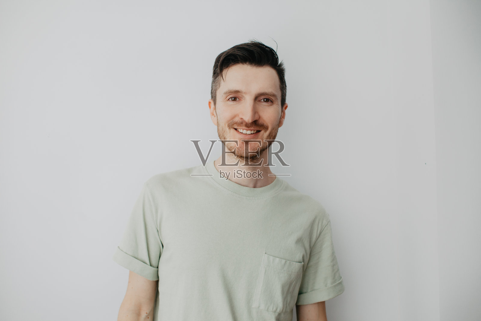 灰墙那边英俊的年轻人，表情严肃。简单自然地看着相机照片摄影图片