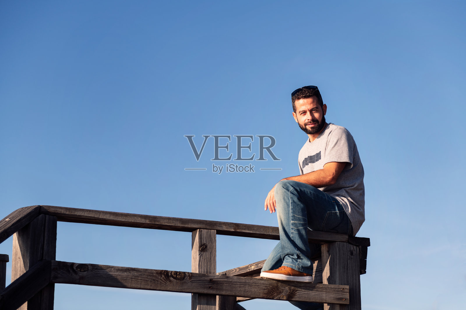 一个人坐在木栏杆上看着摄像机照片摄影图片