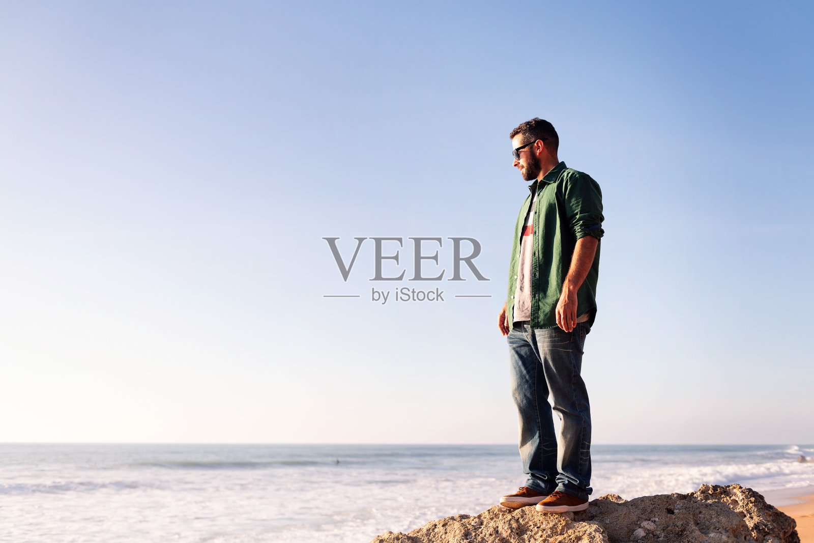 一个戴着墨镜看着大海的大胡子男人照片摄影图片