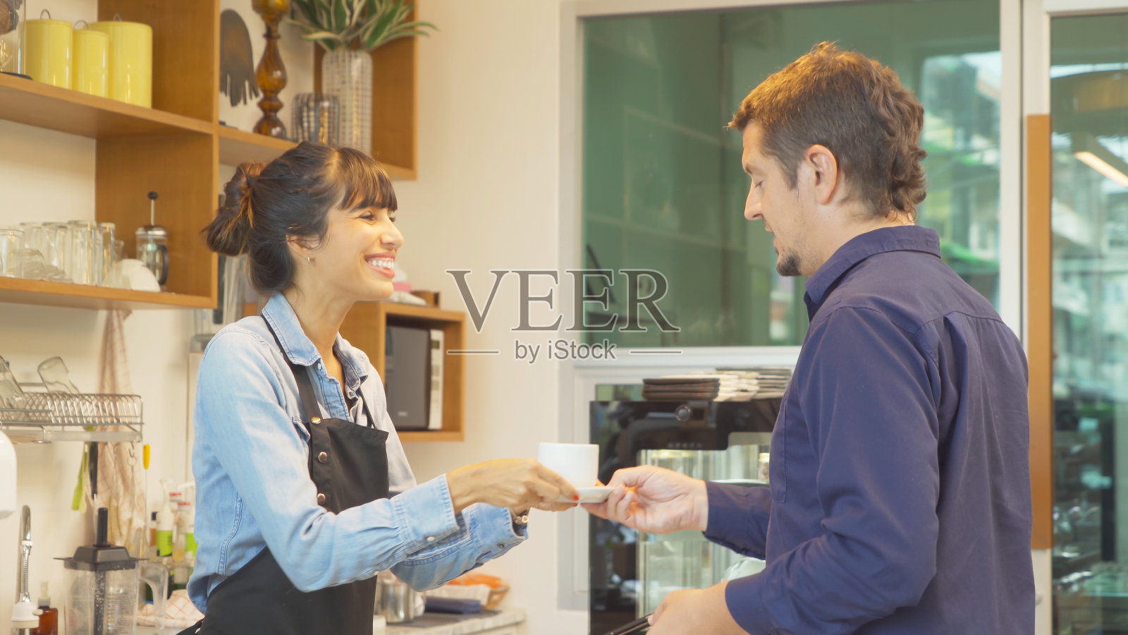 穿着围裙的拉丁咖啡师在柜台收单，和顾客交谈，咖啡店，咖啡厅收银员。业务服务。人们的生活方式。照片摄影图片