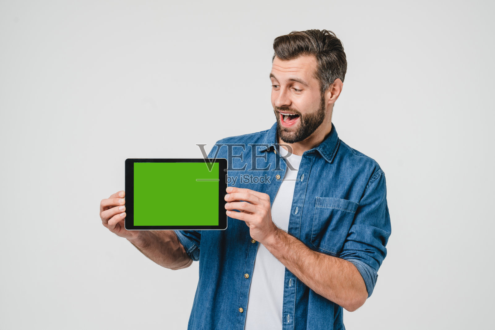 绿色模型屏幕广告copyspace空闲空间。一名白人年轻人手持数码平板电脑，在屏幕上显示手机应用程序，在线社交媒体被隔离在白色中照片摄影图片