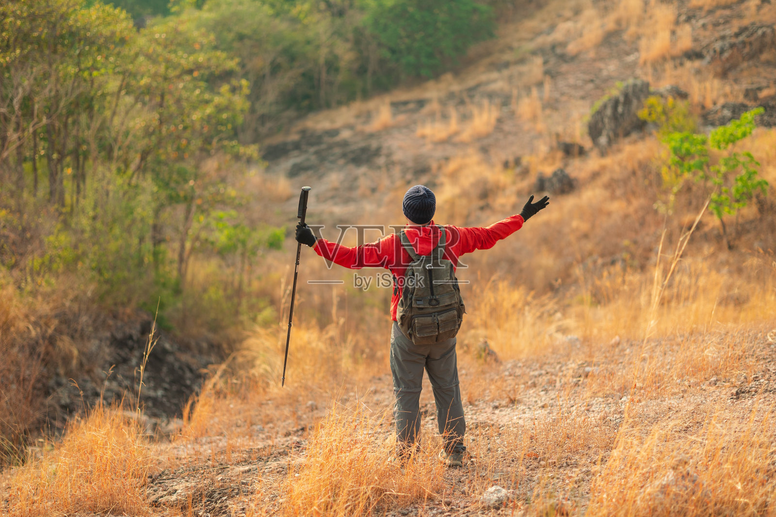 亚洲的年轻人征服了人生目标的顶峰。年轻的亚洲人登山穿夹克走在户外。带背包和登山杖的徒步旅行者。照片摄影图片