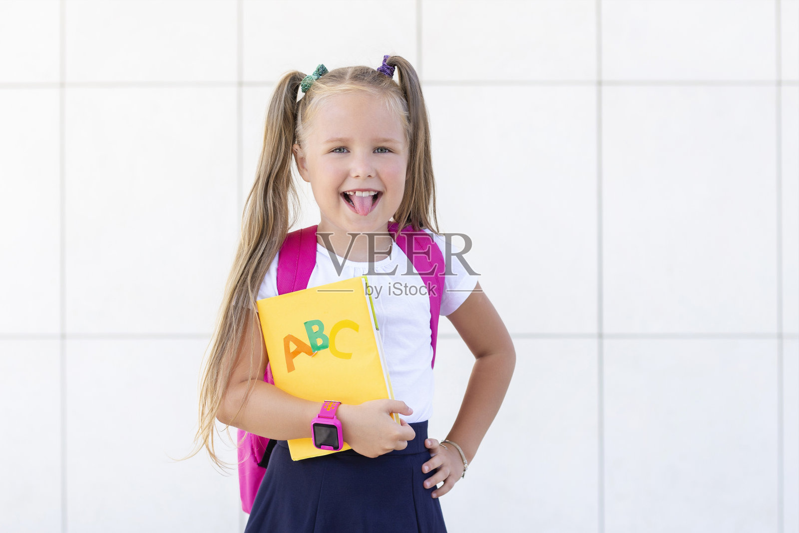 一个女生背着书包，拿着课本站在那里。显示的舌头照片摄影图片