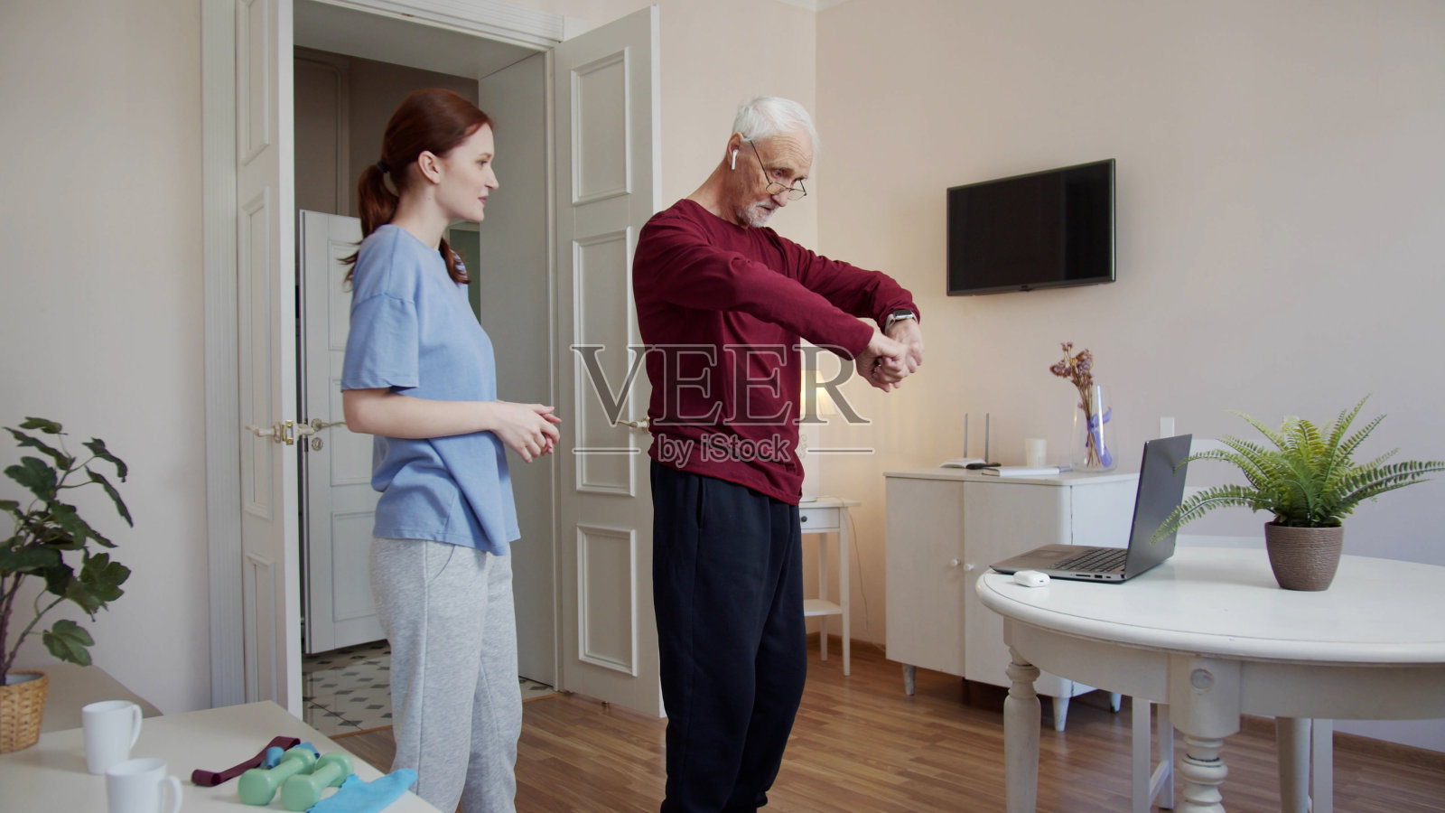 一位妇女在晨练前帮一位老人戴上无线耳机照片摄影图片