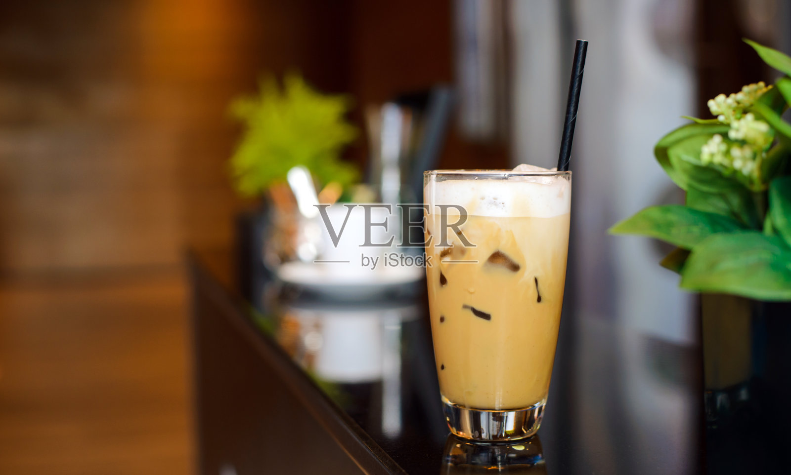 在现代咖啡厅的柜台上为顾客准备了一杯白色的冰咖啡。咖啡休息。照片摄影图片