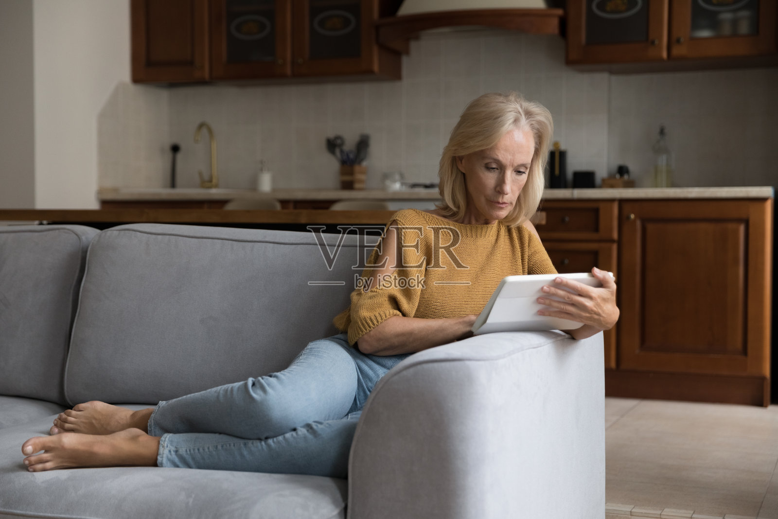 专注于在家中使用平板电脑的中年女性顾客照片摄影图片