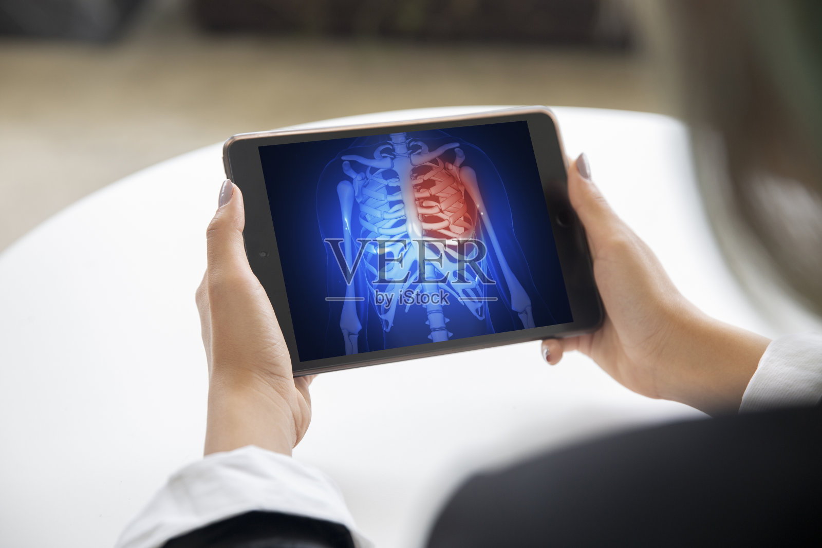 关节处的骨头骨折。医生的手看着蓝色平板屏幕上的红色受损区域。心脏病的概念。照片摄影图片