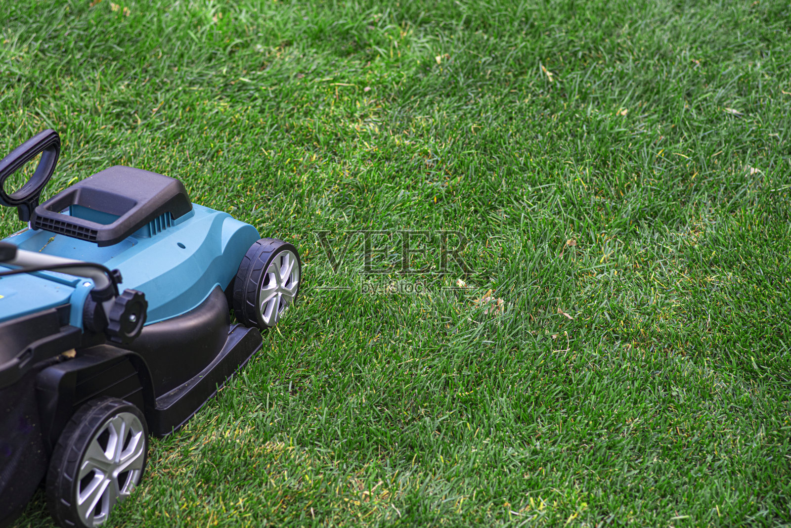 绿色草坪上的电动割草机。照片摄影图片