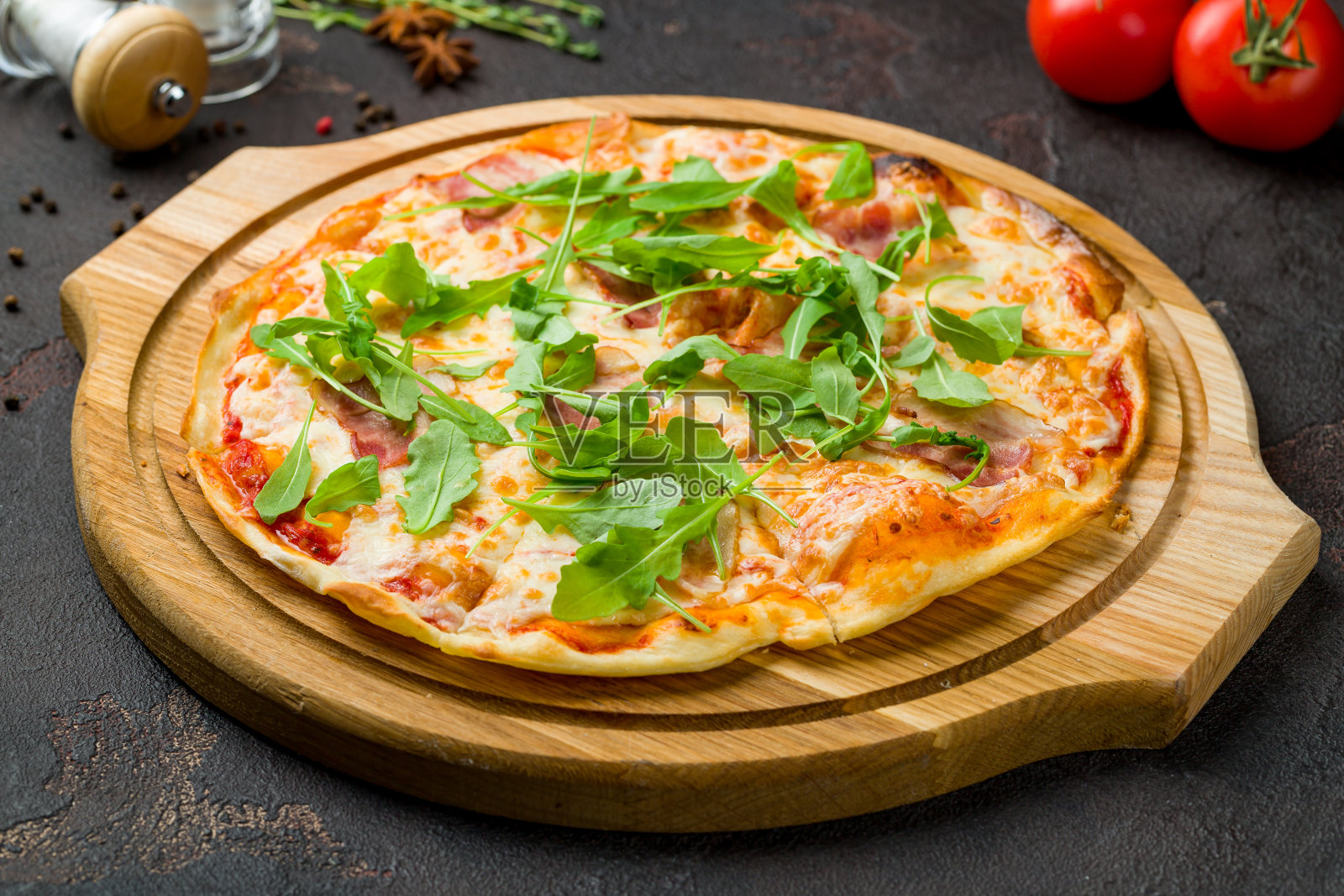 深色混凝土桌子上放着培根和芝麻菜披萨照片摄影图片