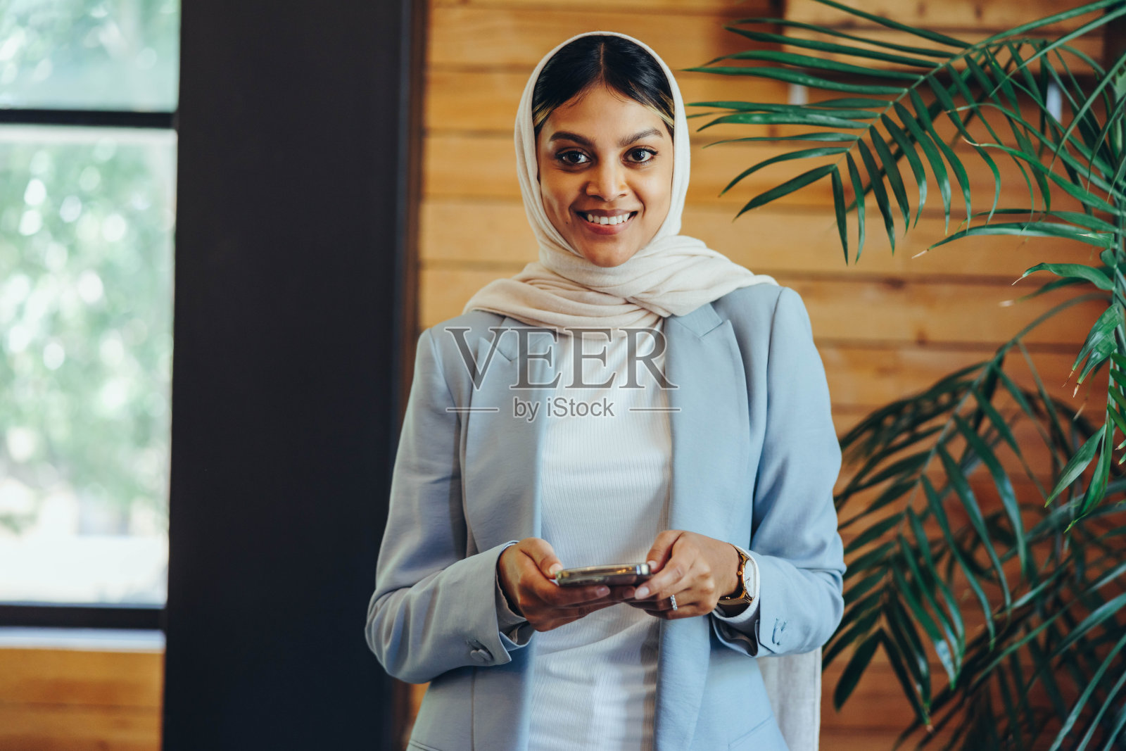 快乐的穆斯林女商人在办公室里拿着智能手机照片摄影图片