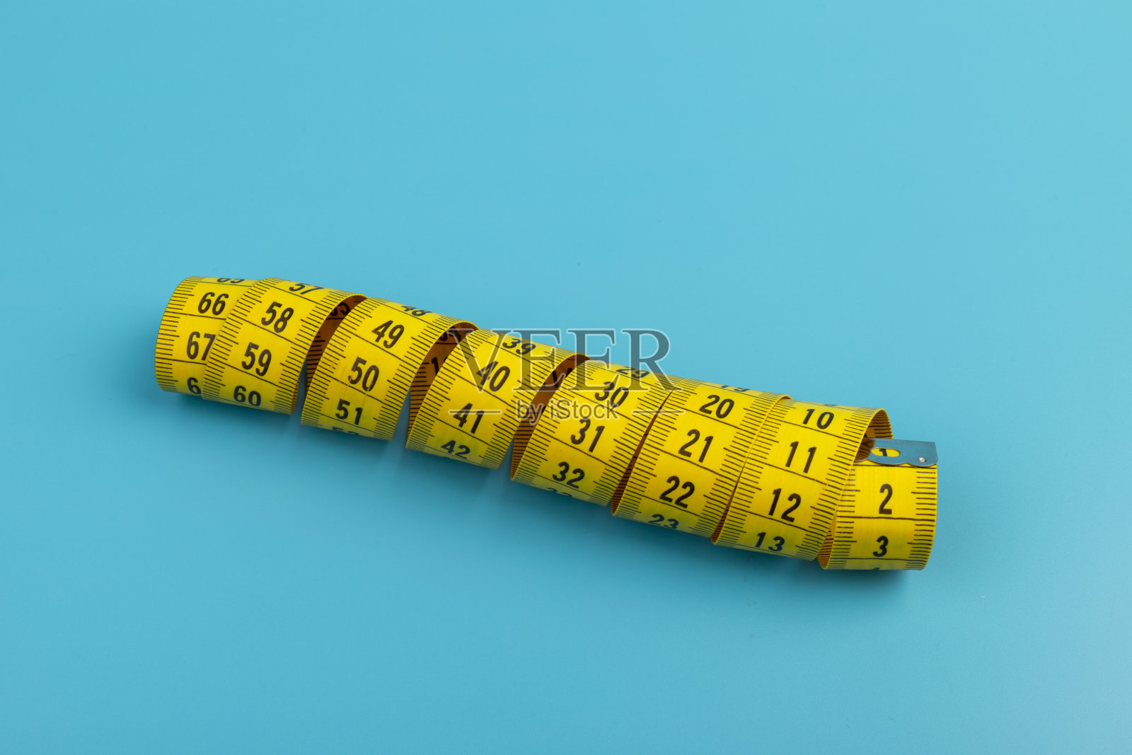 黄色螺旋卷尺在蓝色背景上测量。厘米。空间的文本。照片摄影图片